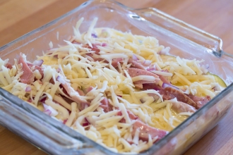First layer of alternating rows of thin potato slices and ham, topped with onions and Swiss cheese