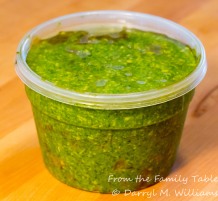 Pesto stored under olive oil in an air-tight container, refrigerated