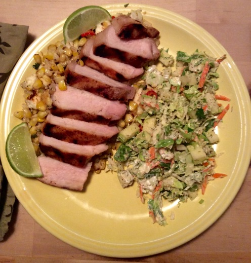 Grilled pork chop on bed of esquites with Brussels sprout slaw